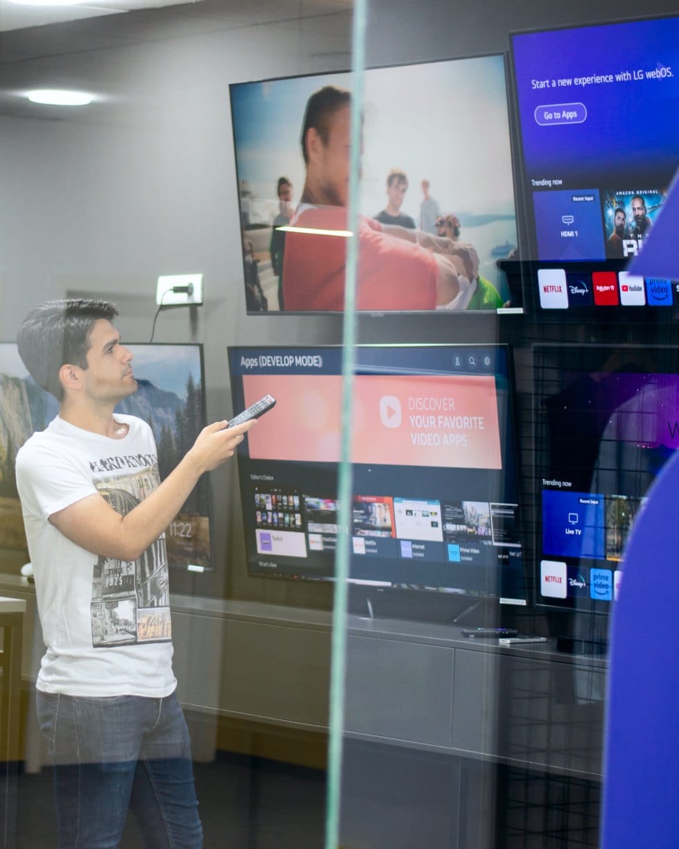 A 2Coders engineer testing streaming apps on a wall of televisions in the studio's device lab